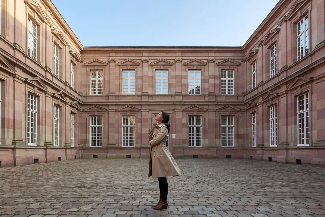 Cour intérieure pavée du château des Rohan de Saverne avec visiteuse observant la façade en grès rose